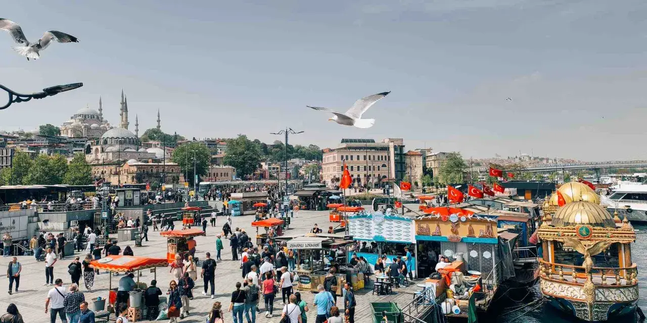 Un vivace mercato sul lungomare di Istanbul, con bancarelle di cibo, barche e la moschea sullo sfondo. Un momento perfetto per capire quando andare a Istanbul.