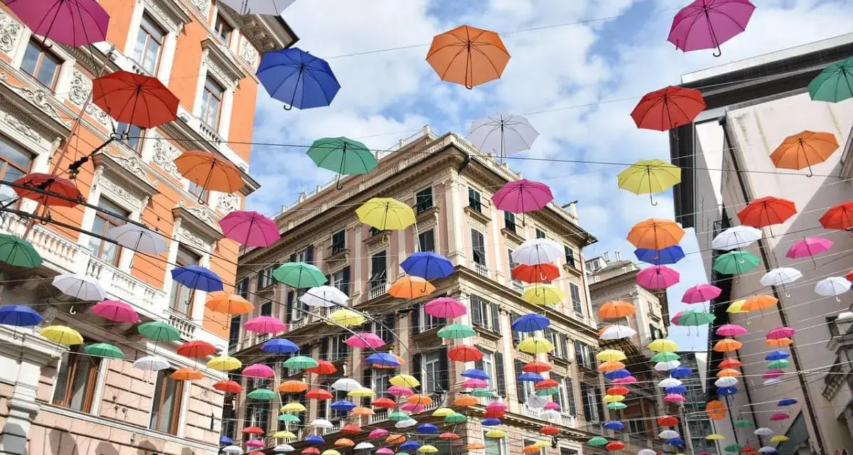 Un cielo di ombrelli colorati sopra i palazzi di Genova. Un'installazione suggestiva, perfetta per scoprire cosa vedere a Genova in 3 giorni.
