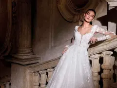 Modella con abiti da sposa per sembrare più alte, posa su una scala di pietra antica.