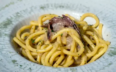 Bucatini con acciughe e cipolla, un classico tra i piatti tipici di Padova, conditi con prezzemolo fresco.