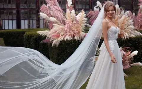 La sposa sorride, il suo abito bianco e il velo fluttuano dolcemente tra le pampas rosa.