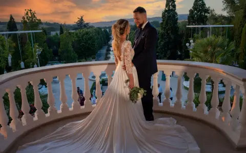 Coppia felice sul balcone al tramonto, con un abito da sposa da favola. Il loro fidanzamento ufficiale è celebrato in un'atmosfera magica.