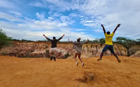Tre amici saltano felici in Kenya, un'esperienza indimenticabile che vale ogni euro del costo safari Kenya.