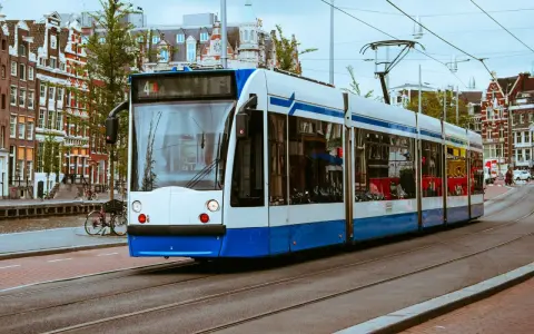 Un tram bianco e blu sferraglia sui binari, un modo efficiente per capire come muoversi ad Amsterdam tra case storiche e canali.