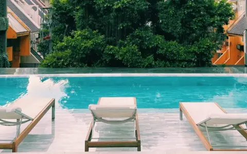Piscina con lettini e vegetazione lussureggiante, un'oasi perfetta per sapere dove dormire a Bangkok.