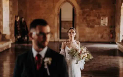La sposa, con un bouquet rustico, attende il suo sposo in un'antica sala. Un venerdì speciale per sposarsi.