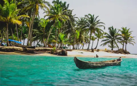 Barca in un mare turchese, palme e spiaggia. Un'idea perfetta per sapere dove andare al mare a Capodanno.
