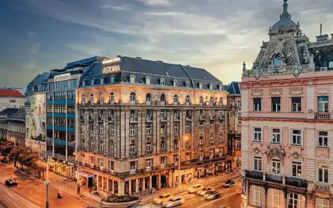 Hotel Astoria, un'ottima scelta per dove alloggiare a Budapest, si affaccia su una strada trafficata con auto gialle sfocate.