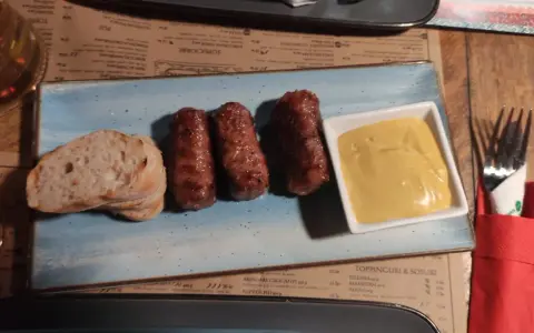 Mici e pane: un assaggio di cosa mangiare a Bucarest. Salsicce grigliate servite con pane fresco e senape.