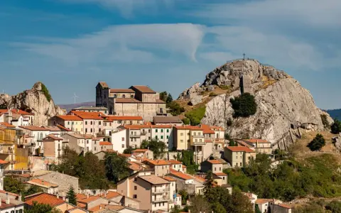Borgo arroccato con case dai tetti rossi, una chiesa imponente e una roccia con croce in cima. Un luogo da scoprire tra le meraviglie di cosa vedere in Molise.