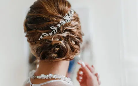 Splendida acconciatura alta sposa con fermaglio scintillante e collana di perle.