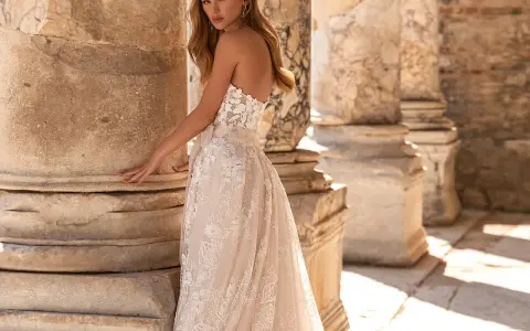 Modella con un abito da sposa in pizzo, tra colonne antiche. Il costo abito da sposa è un investimento per un sogno.
