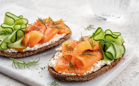 Smørrebrød con salmone affumicato, cetrioli e aneto. Un'idea su cosa mangiare a Copenaghen per un pranzo leggero e gustoso.