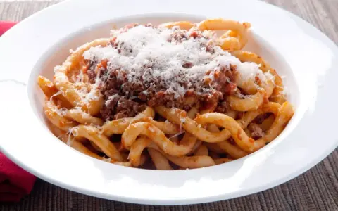Pici al ragù, un classico da provare per scoprire cosa mangiare a Siena. Pasta fatta a mano con sugo di carne e abbondante pecorino.