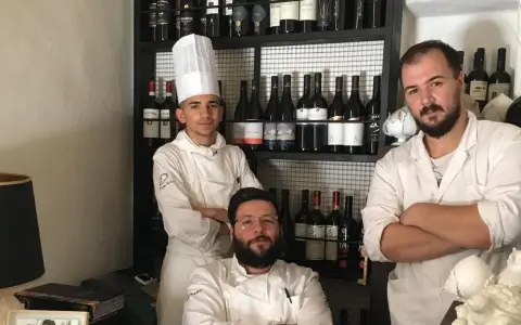 Tre chef posano davanti a una cantina di vini in un ristorante stellato Puglia.
