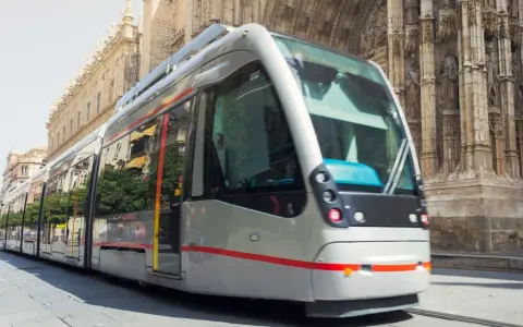 Tram moderno sfreccia davanti alla cattedrale, un modo efficiente per capire come muoversi a Siviglia.