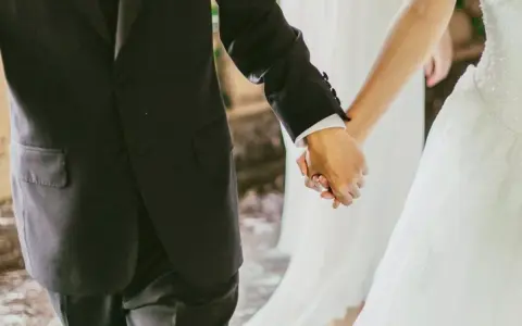 Mani intrecciate, un uomo in abito scuro e una sposa in bianco. Il vero significato di sposa è l'amore che unisce.