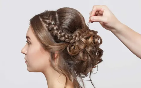 Treccia semiraccolto, un'acconciatura sposa elegante con ricci morbidi e una mano che aggiunge un fermaglio.