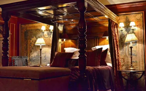 Lussuosa camera da letto con letto a baldacchino, arazzi storici e lampade eleganti. Un'idea di dove dormire a Edimburgo per un soggiorno da re.