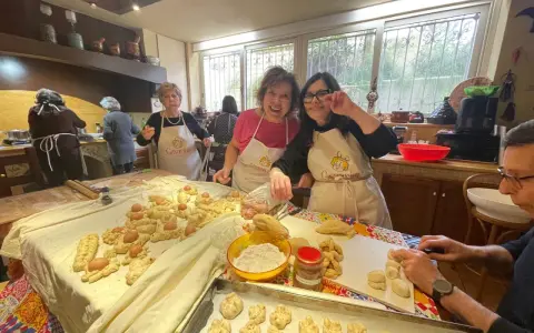 Donne sorridenti preparano impasti per piatti tipici di Perugia, con uova e pane intrecciato.
