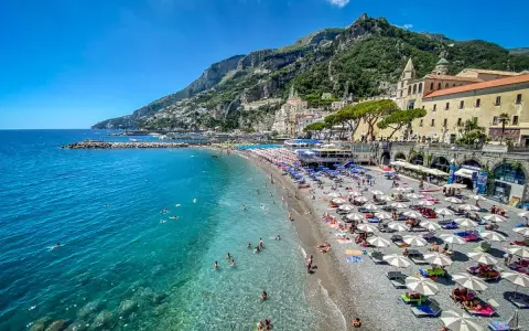 Spiaggia affollata con ombrelloni e gente che nuota, un'ottima idea per un weekend in Italia con vista sulla costa.