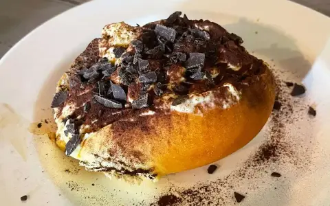Un dolce al cucchiaio, forse un tiramisù rivisitato, con cacao e scaglie di cioccolato. Un'idea golosa su cosa mangiare a Roma.