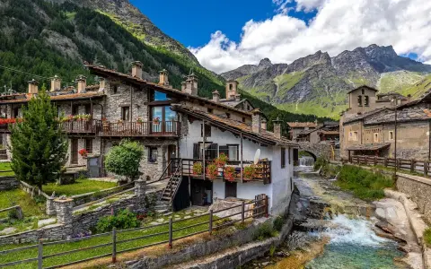Un incantevole borgo da visitare in Piemonte, con case in pietra, balconi fioriti e un torrente che scorre tra le montagne.