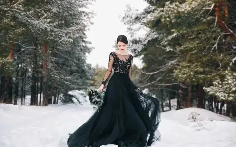 Una sposa in un bosco innevato indossa un abito da sposa nero, un simbolo di audacia e individualità.