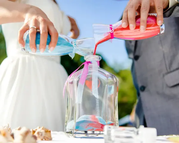 Sposi uniscono sabbia blu e rossa in un vaso, un simbolo del rito della sabbia che unisce le loro vite.