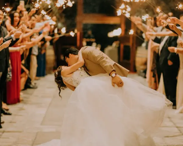 La sposa e lo sposo si baciano tra le scintille dei bengala, circondati da amici e parenti festanti. Un momento magico che sembra uscito da un gioco.