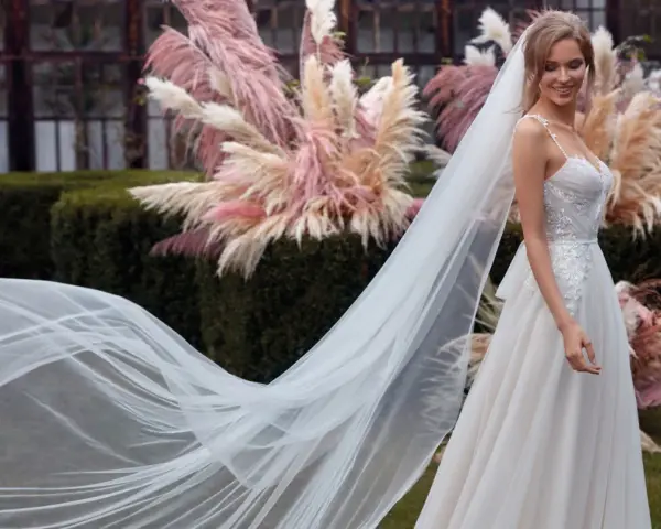 La sposa sorride, il suo abito bianco e il velo fluttuano dolcemente tra le pampas rosa.