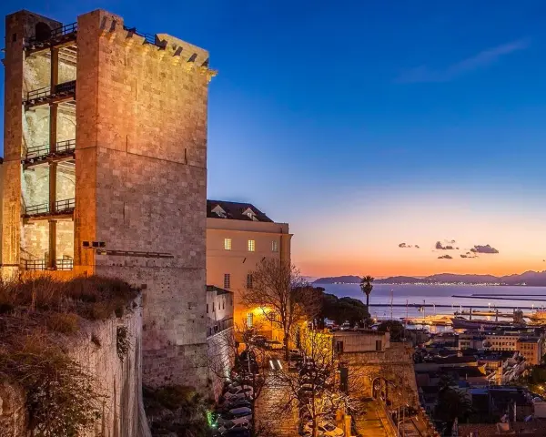 Torre medievale illuminata al tramonto, con vista sul porto e sul mare. Un'ottima anteprima di cosa vedere a Cagliari in un giorno.