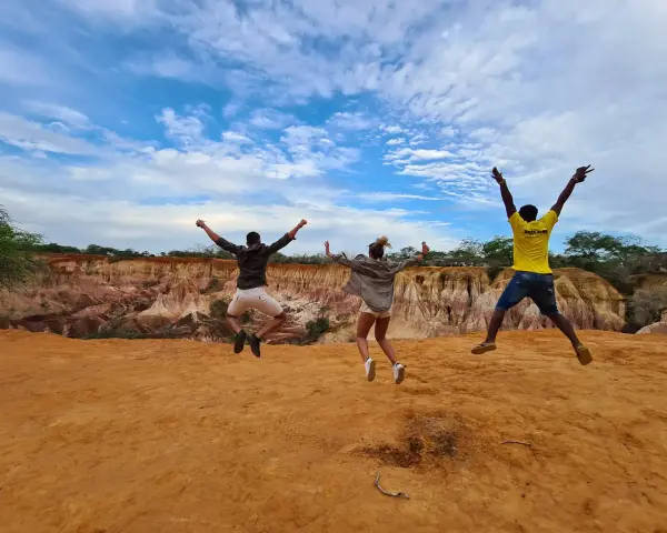Tre amici saltano felici in Kenya, un'esperienza indimenticabile che vale ogni euro del costo safari Kenya.