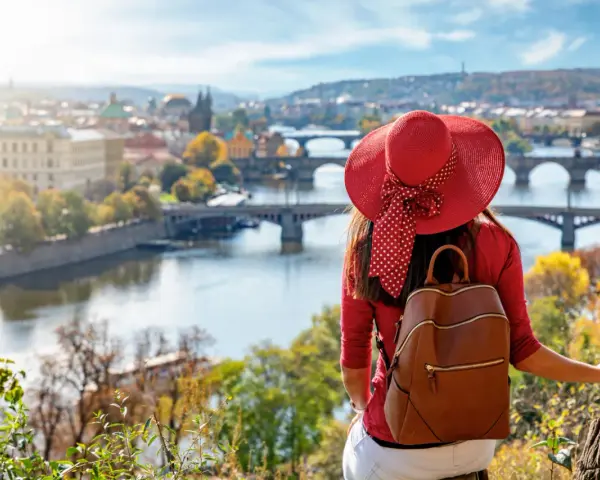 Donna con cappello rosso ammira Praga in autunno. Il periodo migliore per andare a Praga è quando la natura si tinge di colori caldi.