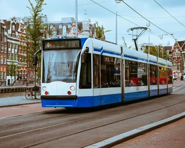 Un tram bianco e blu sferraglia sui binari, un modo efficiente per capire come muoversi ad Amsterdam tra case storiche e canali.