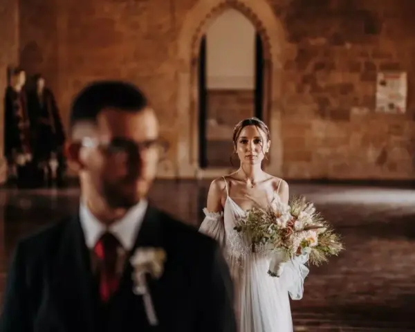 La sposa, con un bouquet rustico, attende il suo sposo in un'antica sala. Un venerdì speciale per sposarsi.