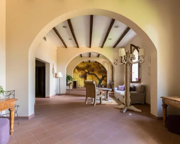 Interno accogliente con archi in pietra, un murale di un albero antico e arredi che evocano l'atmosfera dell'antico borgo di Sutri.