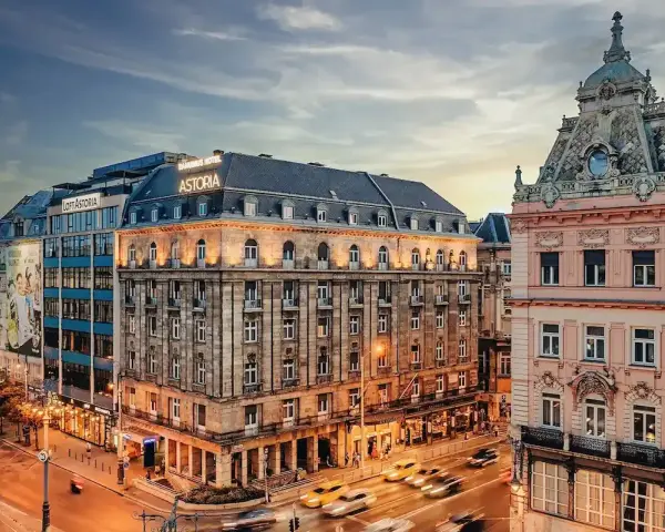 Hotel Astoria, un'ottima scelta per dove alloggiare a Budapest, si affaccia su una strada trafficata con auto gialle sfocate.