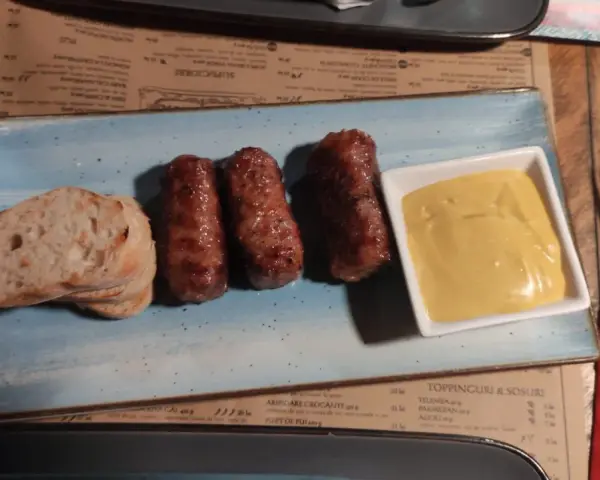 Mici e pane: un assaggio di cosa mangiare a Bucarest. Salsicce grigliate servite con pane fresco e senape.