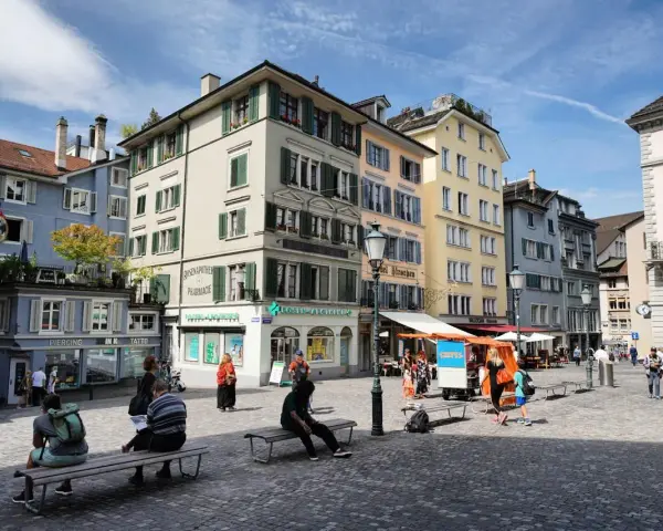 Piazza di Zurigo con edifici colorati, negozi e persone che passeggiano. Ideale per scoprire cosa vedere a Zurigo in un giorno.