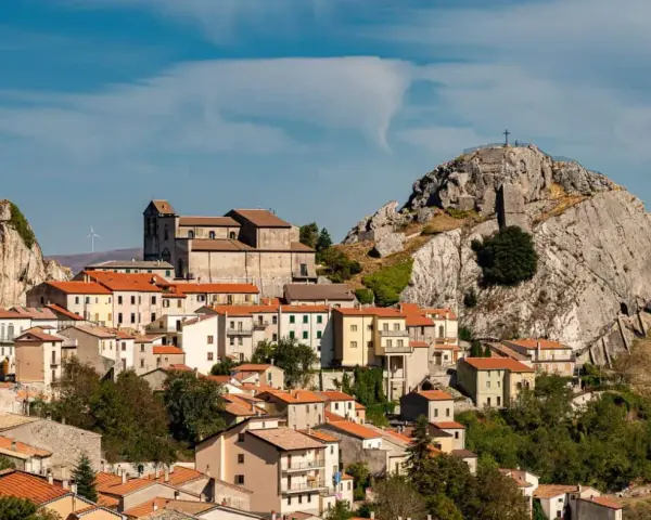 Borgo arroccato con case dai tetti rossi, una chiesa imponente e una roccia con croce in cima. Un luogo da scoprire tra le meraviglie di cosa vedere in Molise.