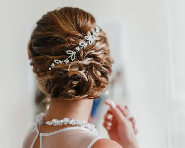 Splendida acconciatura alta sposa con fermaglio scintillante e collana di perle.