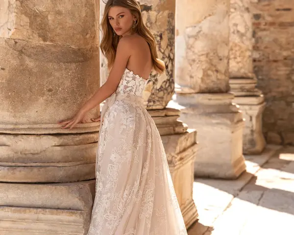 Modella con un abito da sposa in pizzo, tra colonne antiche. Il costo abito da sposa è un investimento per un sogno.