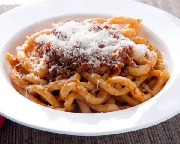 Pici al ragù, un classico da provare per scoprire cosa mangiare a Siena. Pasta fatta a mano con sugo di carne e abbondante pecorino.