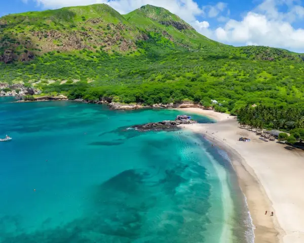 Spiaggia tropicale con mare turchese e montagne verdi. Un vero capo verde, ideale per una vacanza da sogno.