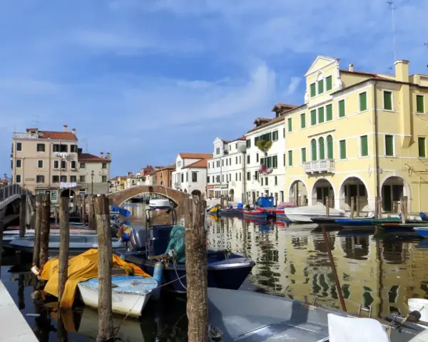 Chioggia cosa vedere: un canale con barche ormeggiate e case colorate che si riflettono sull'acqua.