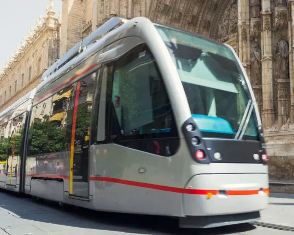 Tram moderno sfreccia davanti alla cattedrale, un modo efficiente per capire come muoversi a Siviglia.