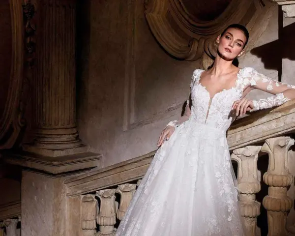 Modella con abiti da sposa per sembrare più alte, posa su una scala di pietra antica.