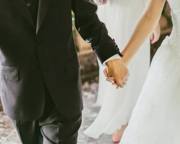 Mani intrecciate, un uomo in abito scuro e una sposa in bianco. Il vero significato di sposa è l'amore che unisce.