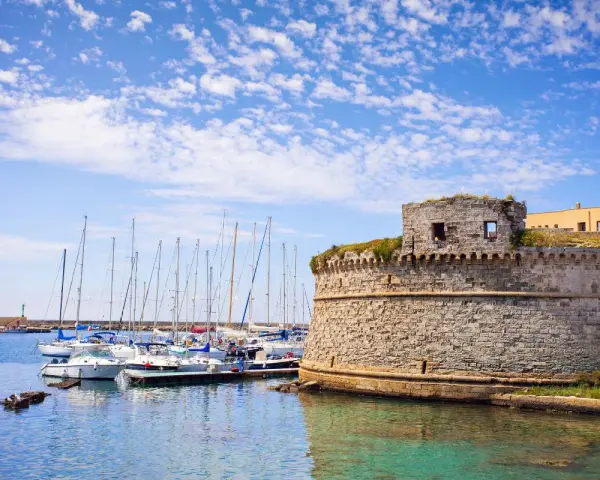 Porto di Gallipoli con castello e barche a vela. Un luogo incantevole per scoprire cosa fare a Gallipoli.